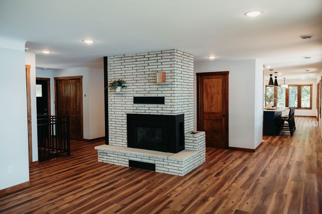Spacious living room with wood floors, brick fireplace, and wooden doors.