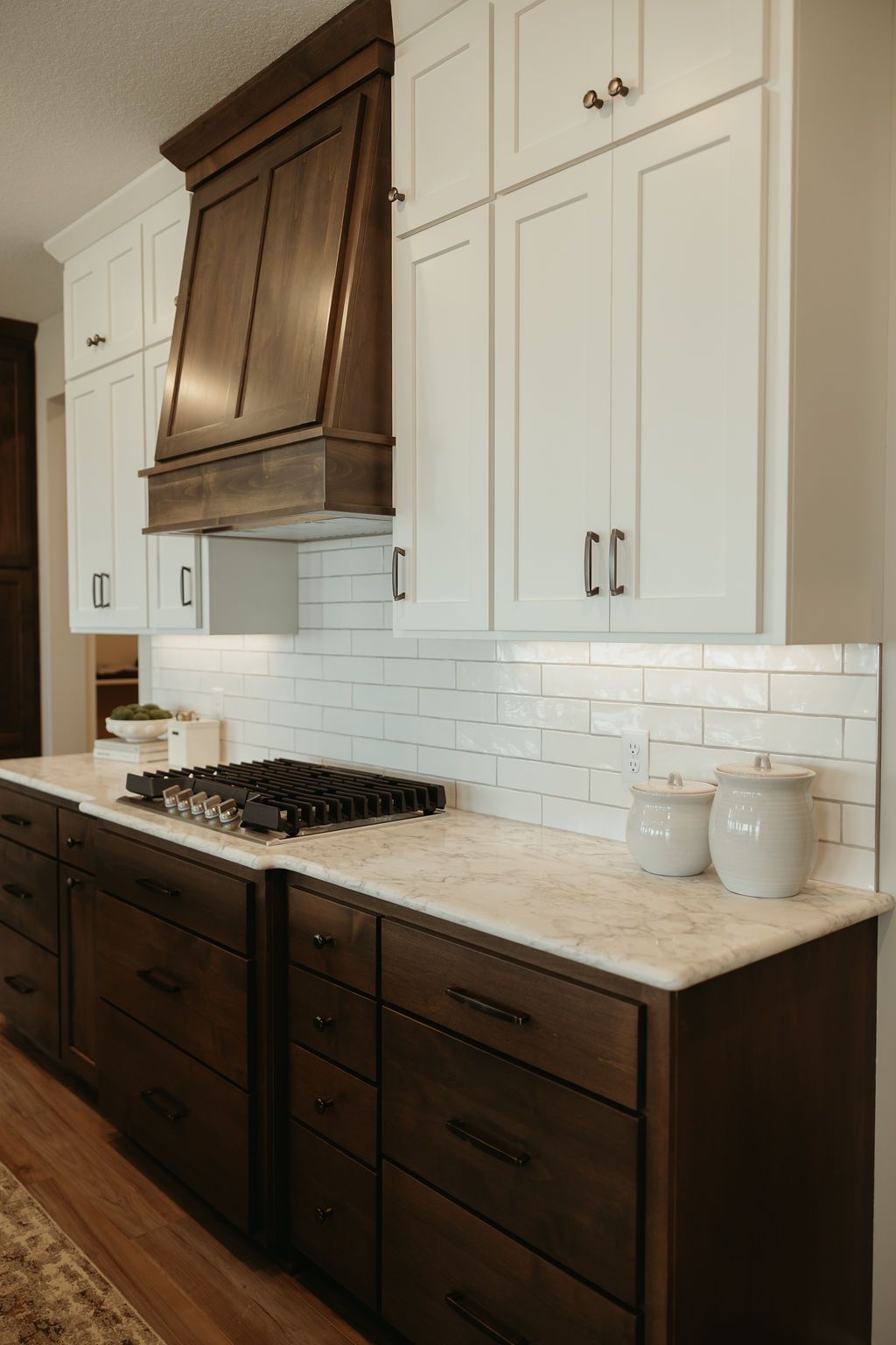 Kitchen with white upper cabinets, brown lower cabinets, and a dark brown hood.
