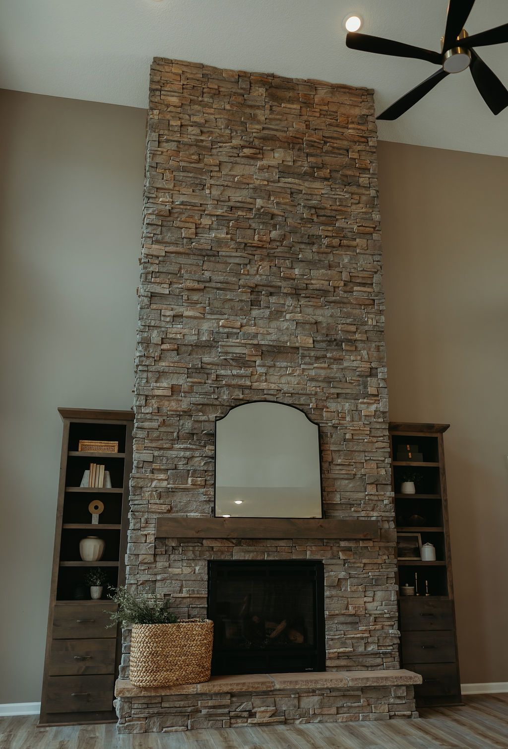 Stone fireplace with mirror and wooden mantel, flanked by bookshelves.