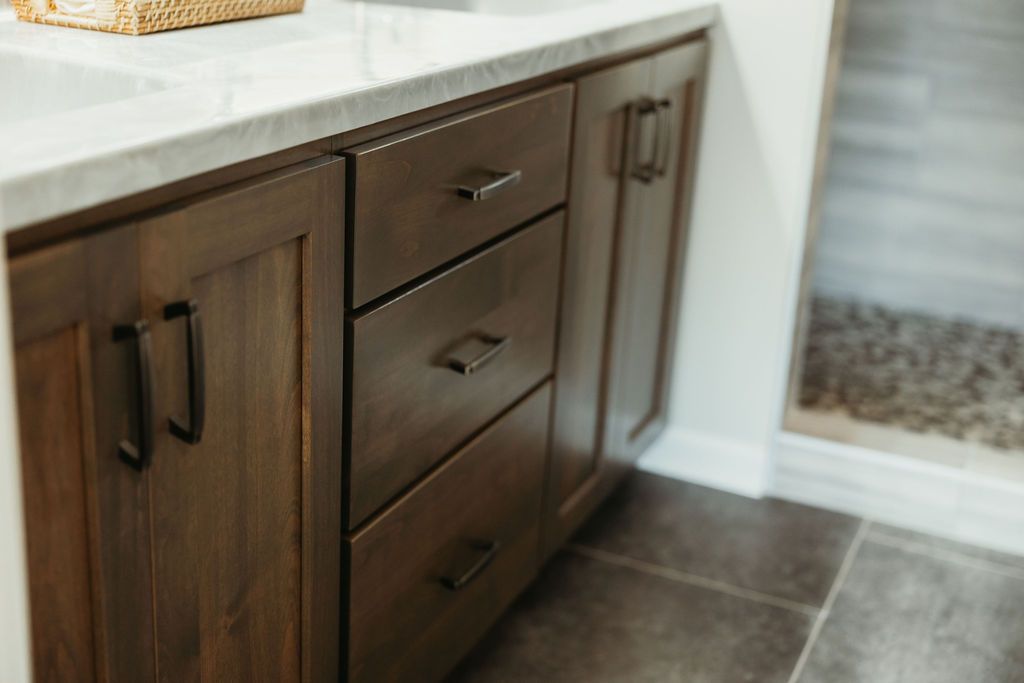 Bathroom vanity with dark brown cabinets, marble countertop, and black hardware.