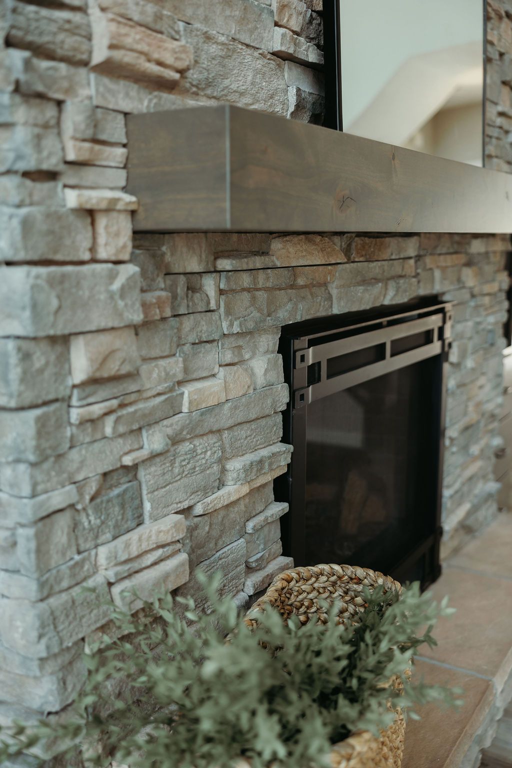Stone fireplace with a dark wooden mantel and a fireplace insert.