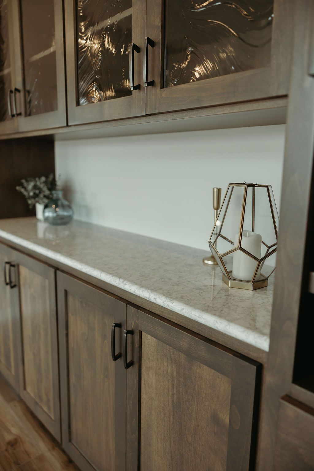 Wooden cabinets with black handles, a light-colored countertop, and glass-fronted upper cabinets.