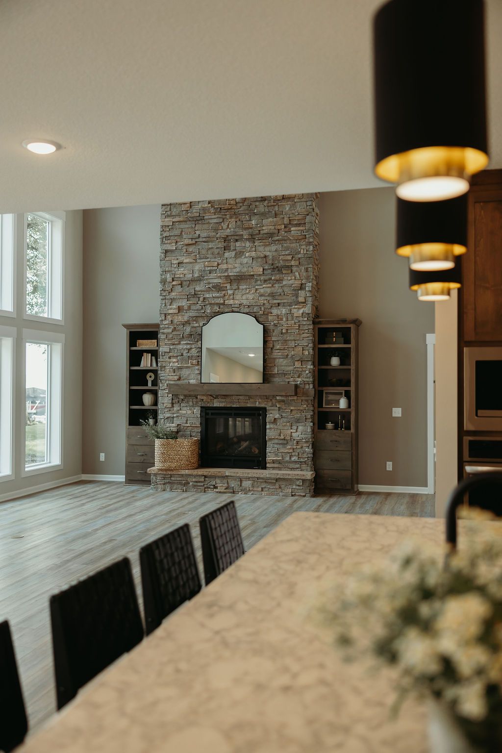Living room with stone fireplace, built-in shelves, and tall windows.