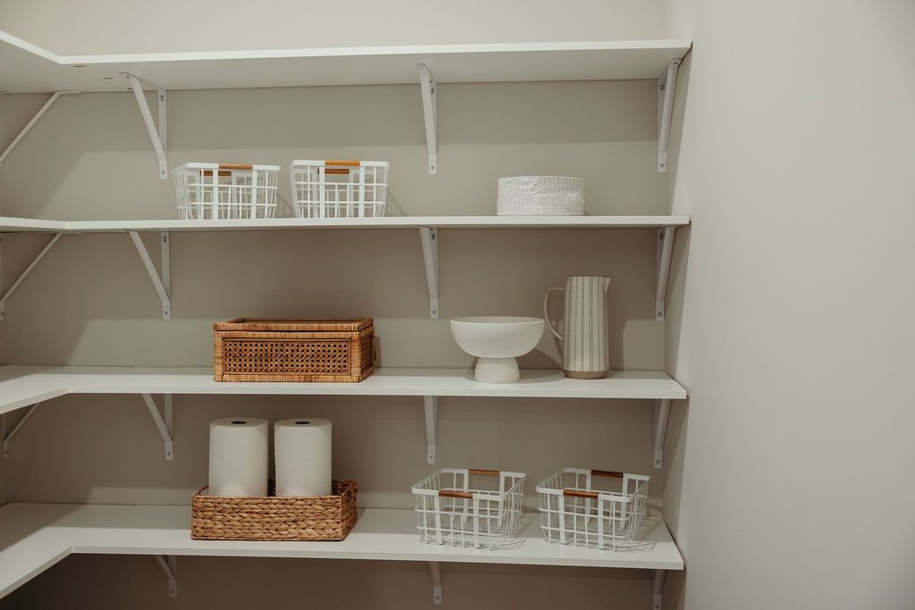 White pantry shelves with various decorative items and baskets.