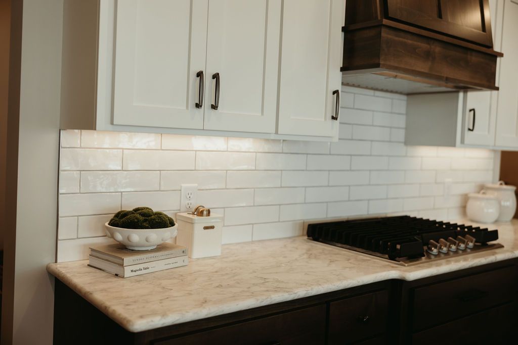 Kitchen with white cabinets, dark countertops, white backsplash, and gas stovetop.