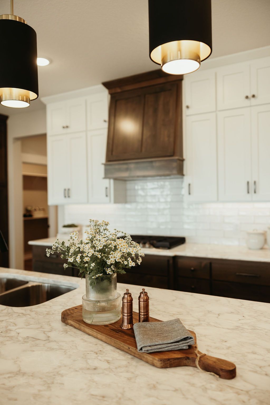 Kitchen with marble countertop, wooden cutting board with flowers, and dark cabinets.