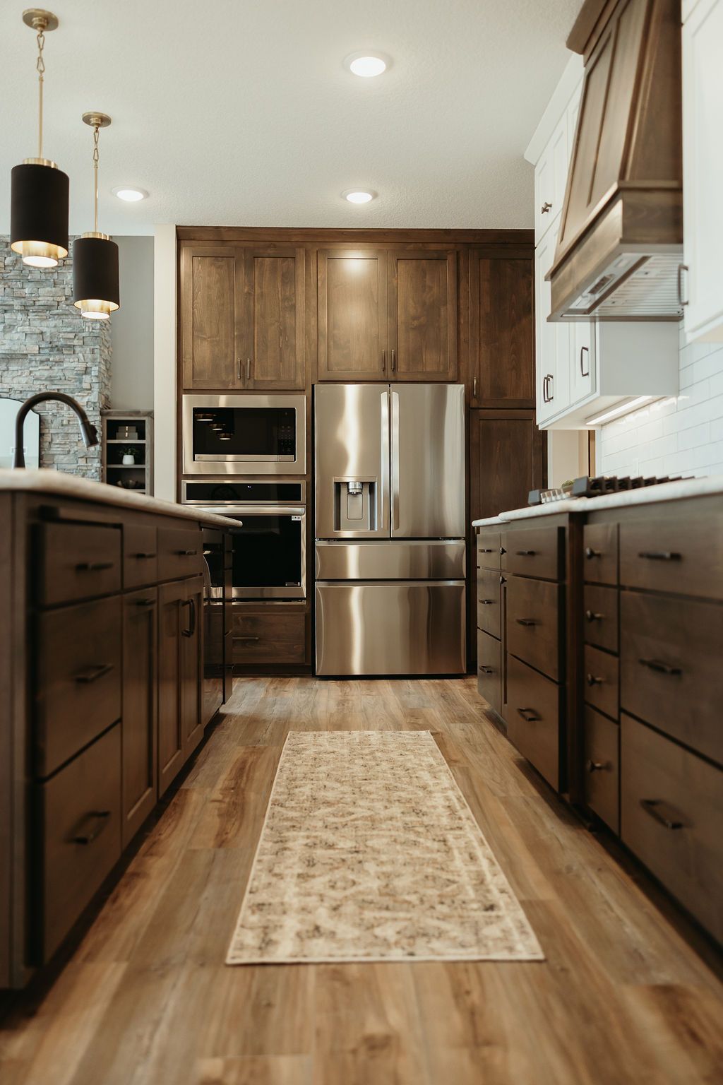 Kitchen with wooden cabinets, stainless steel appliances, and island with pendant lights.