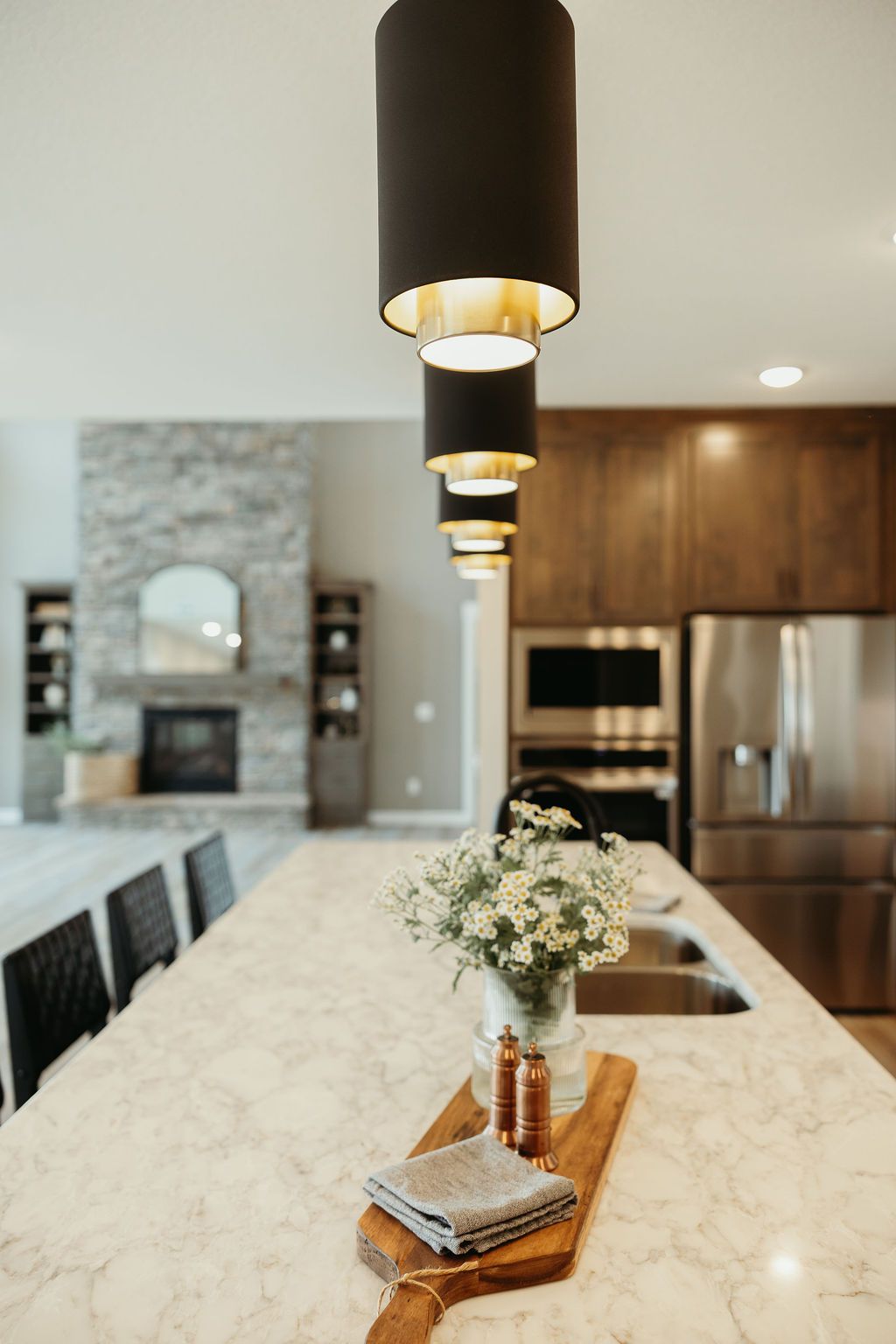 Modern kitchen with island, pendant lights, wooden accents, and a marble countertop.
