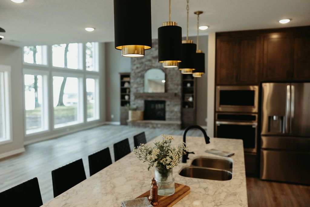 Modern kitchen with island, pendant lights, and large windows overlooking a spacious living area.