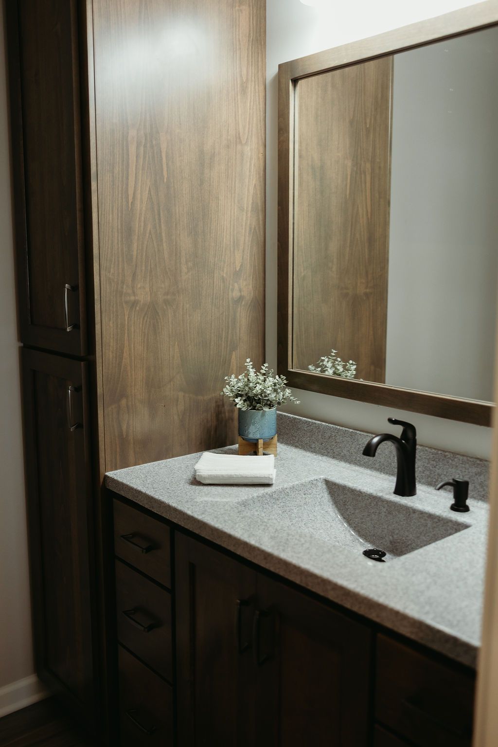 Bathroom with dark wood cabinetry, gray countertop, and black faucet.