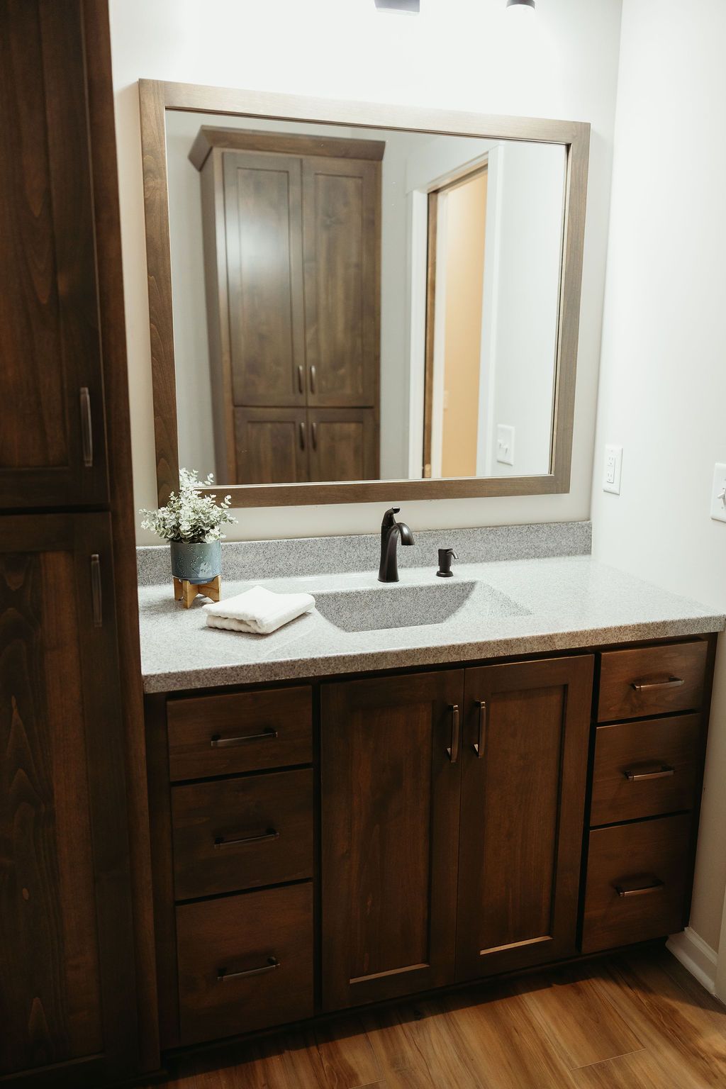 Bathroom with dark wood vanity, light countertop, large mirror, and cabinet.