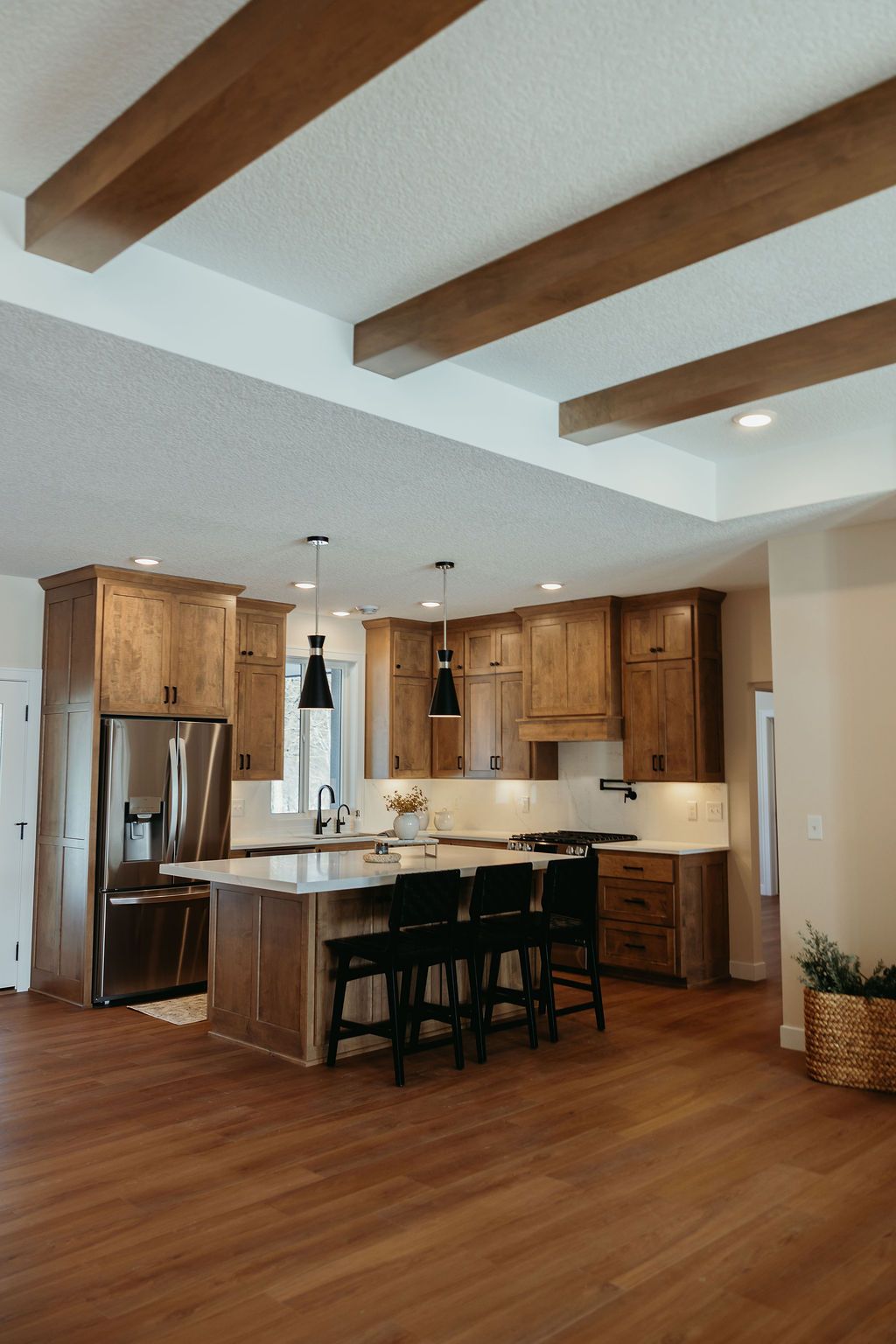 Kitchen with wood cabinets, island, and ceiling beams; stainless steel appliances.