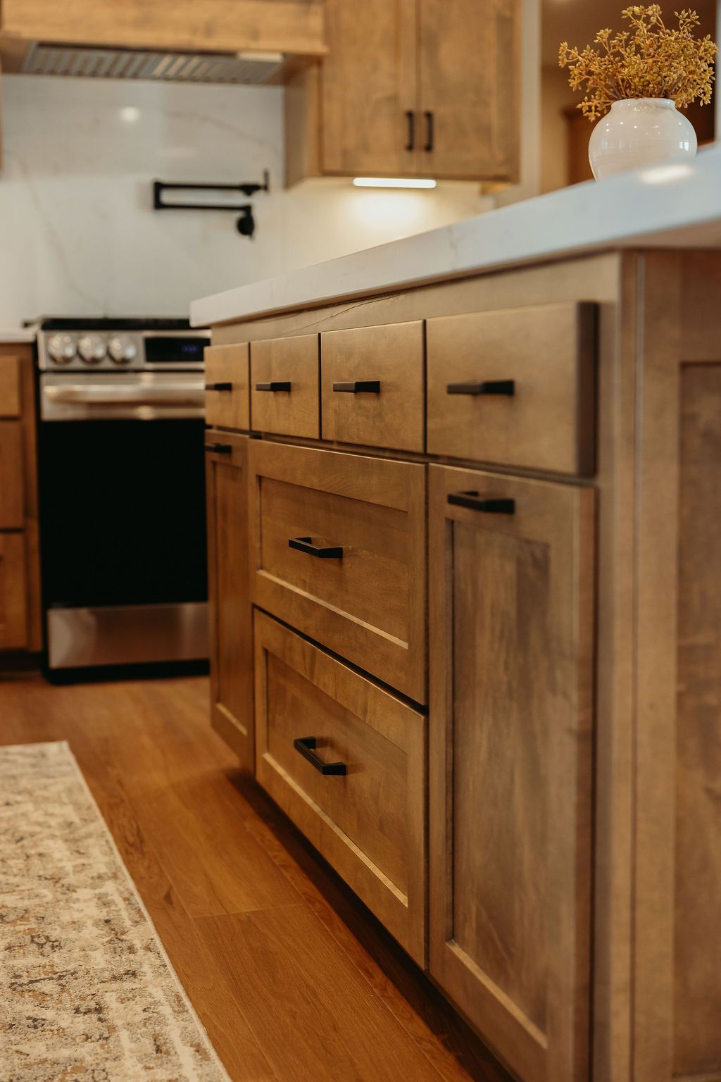 Wooden kitchen island with drawers and cabinets, a stainless steel stove, and light wood flooring.