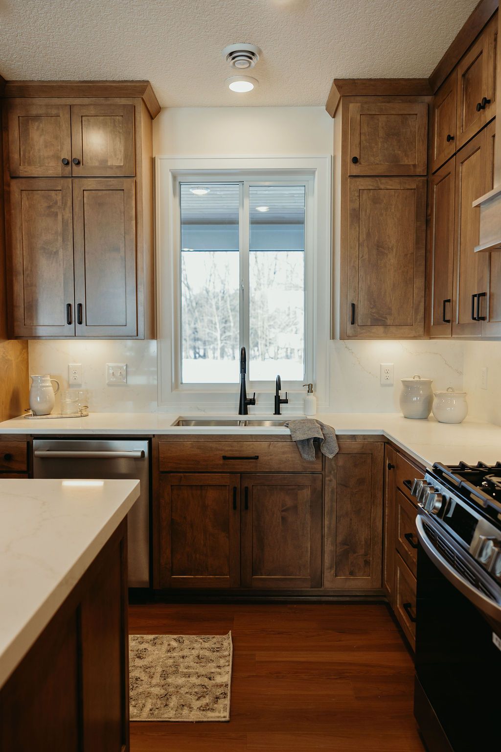 Kitchen with wooden cabinets, white countertops, and a window above the sink.