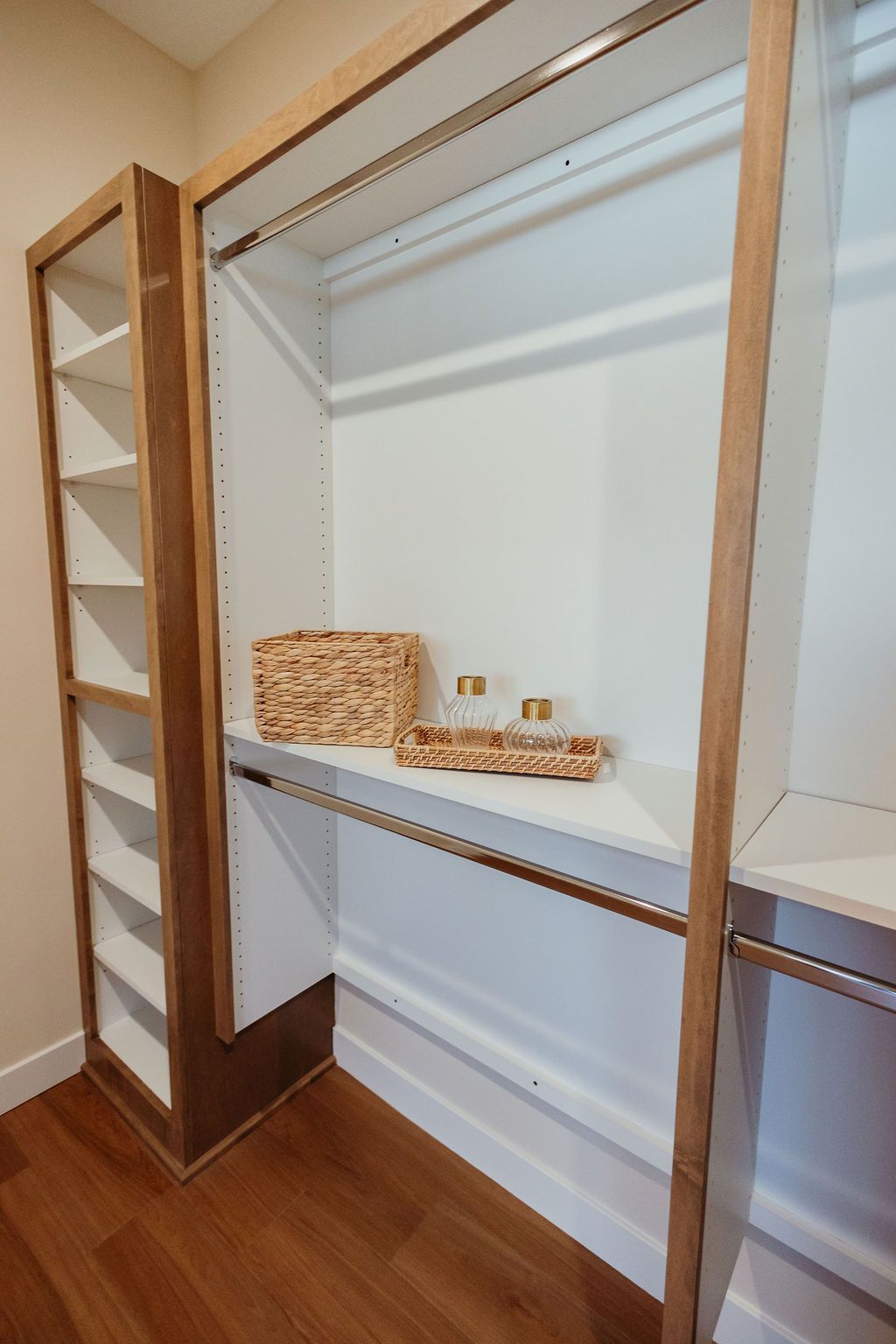 Empty closet with white shelves and wooden accents. Contains a basket and tray.