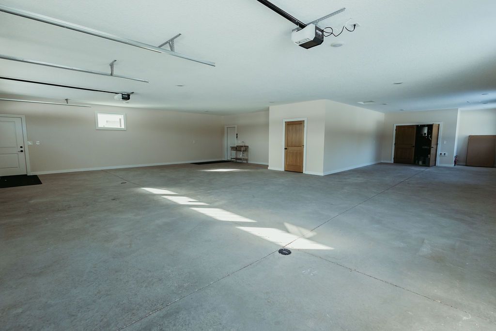 Empty garage with a gray carpeted floor, white walls, and a closed garage door.