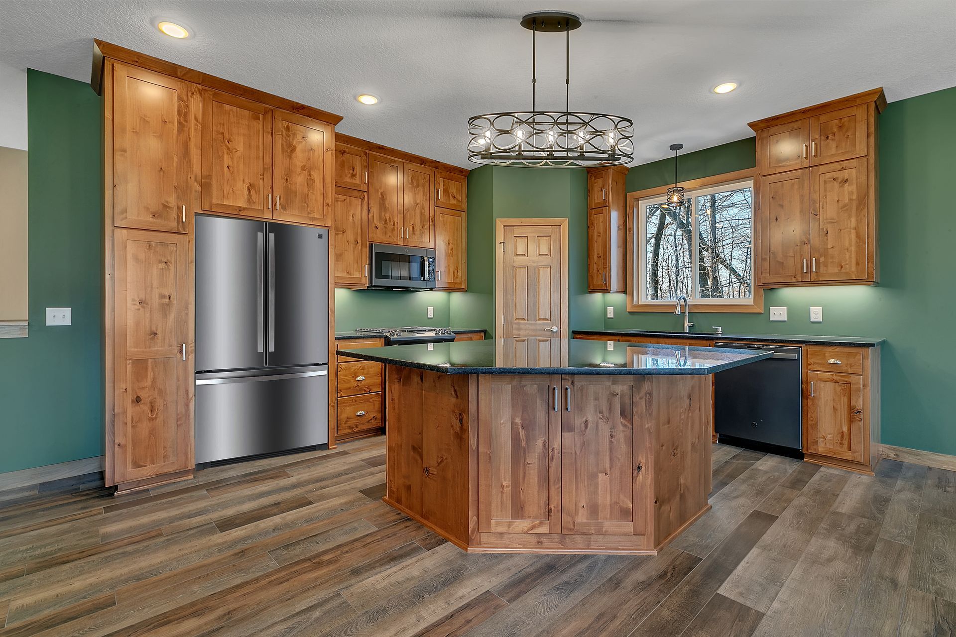 A kitchen with wooden cabinets , stainless steel appliances and a large island.