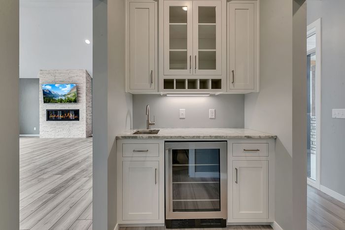 A kitchen with white cabinets and a wine cooler.