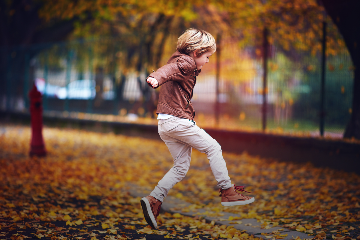 A young boy is jumping in the air in a park.