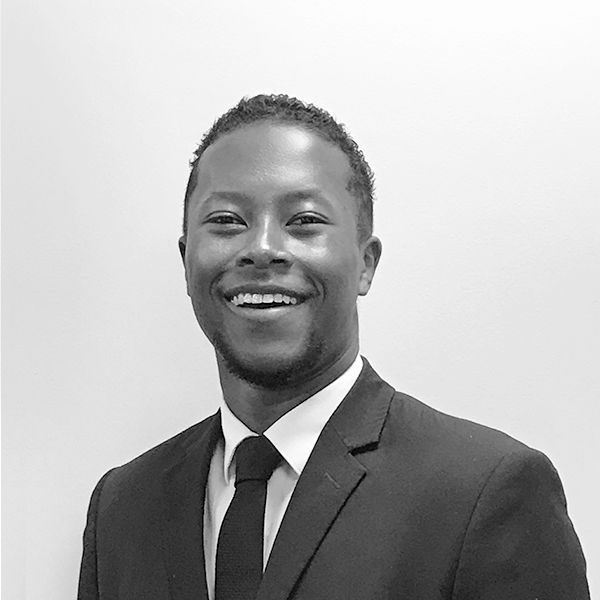 A man in a suit and tie is smiling in a black and white photo.