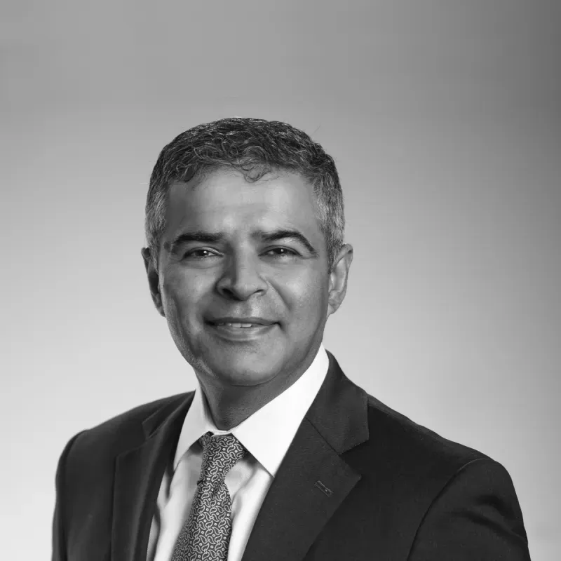 A man in a suit and tie is smiling in a black and white photo.