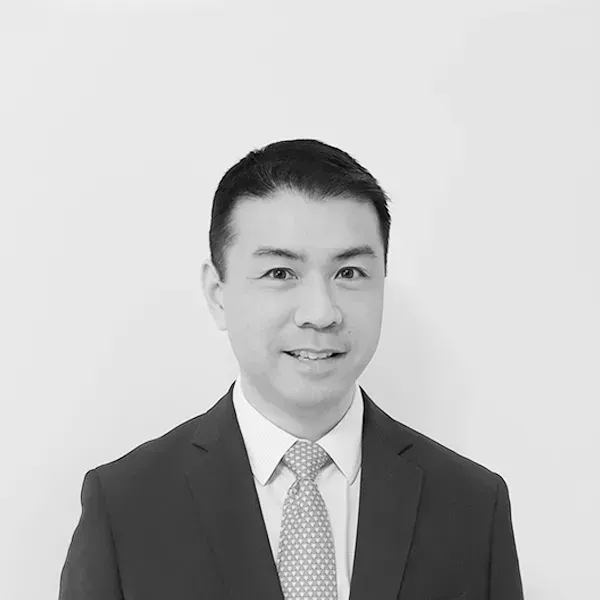 A man in a suit and tie is smiling in a black and white photo.