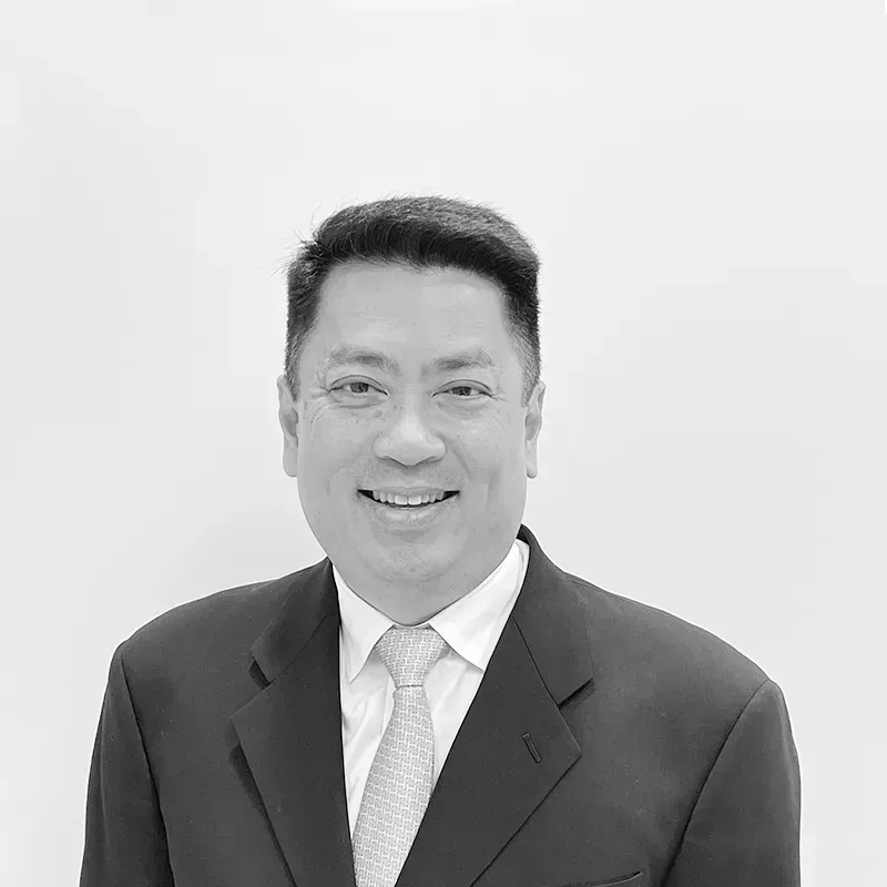 A man in a suit and tie is smiling in a black and white photo.