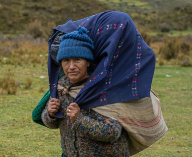Nomadische vrouw draagt bagage op haar rug, symbool systemische last die je in liefde oppakt maar niet van jezelf zijn