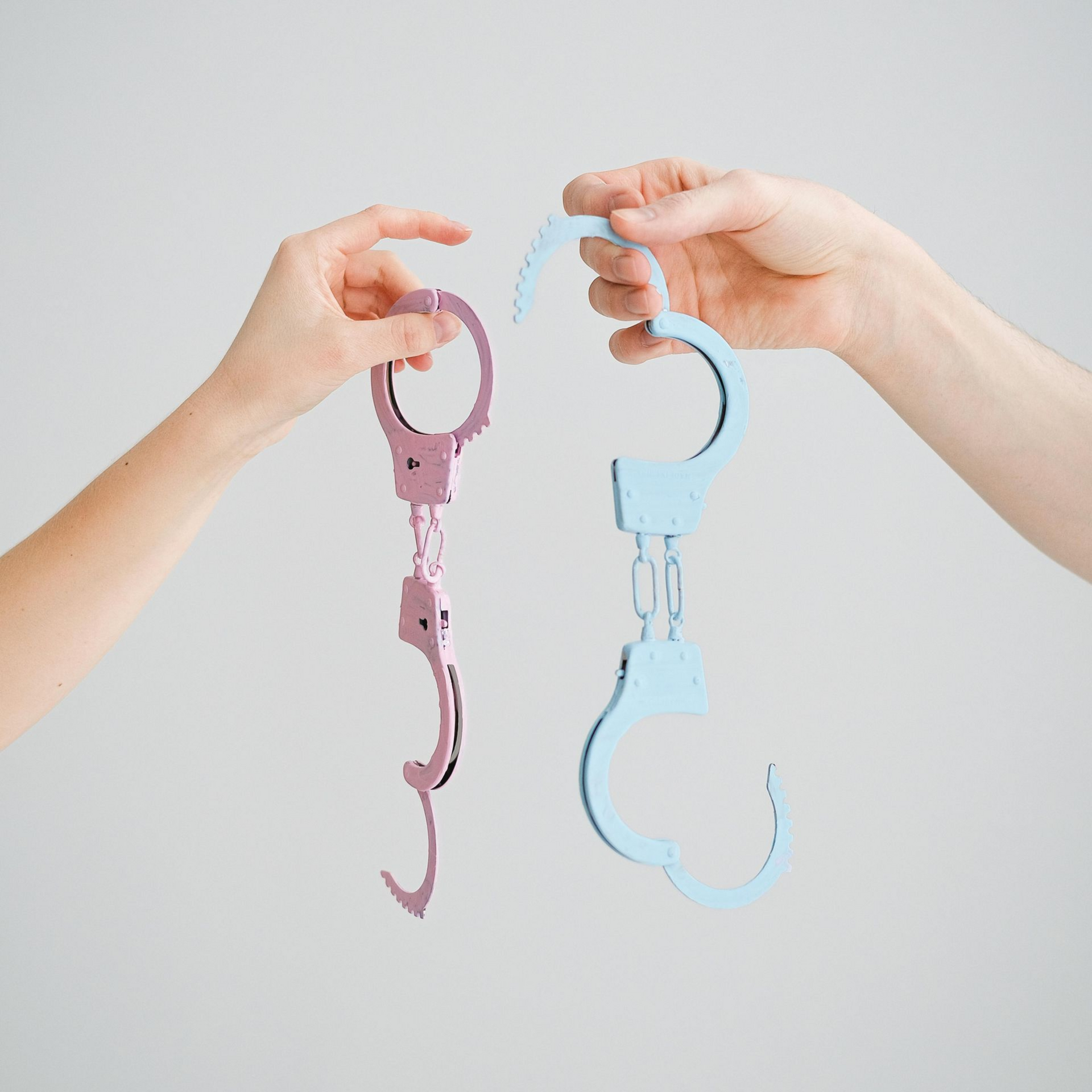 Twee open handboeien, roze en blauw, symbool voor bevrijding van oude genderrollen