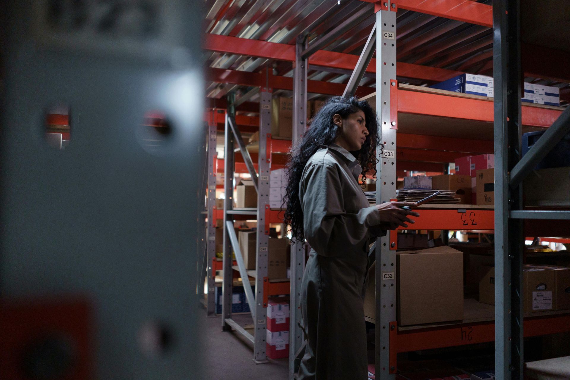 A woman is standing in a warehouse looking at her phone.