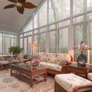 Sunroom with large windows overlooking a misty forest. Floral couch and decor.