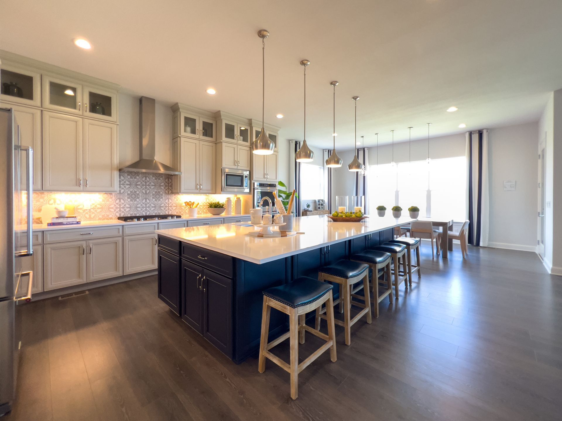 Modern kitchen with a large island, pendant lights, white cabinets, and bar stools
