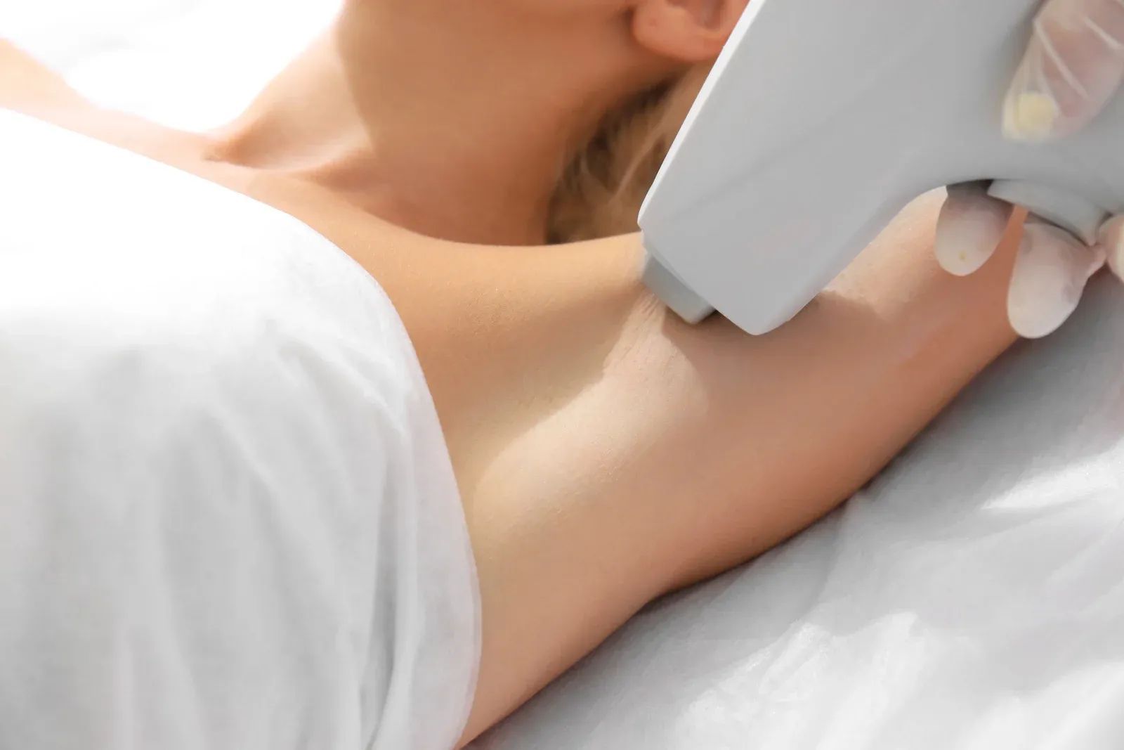 A woman is getting a laser hair removal treatment on her underarm.