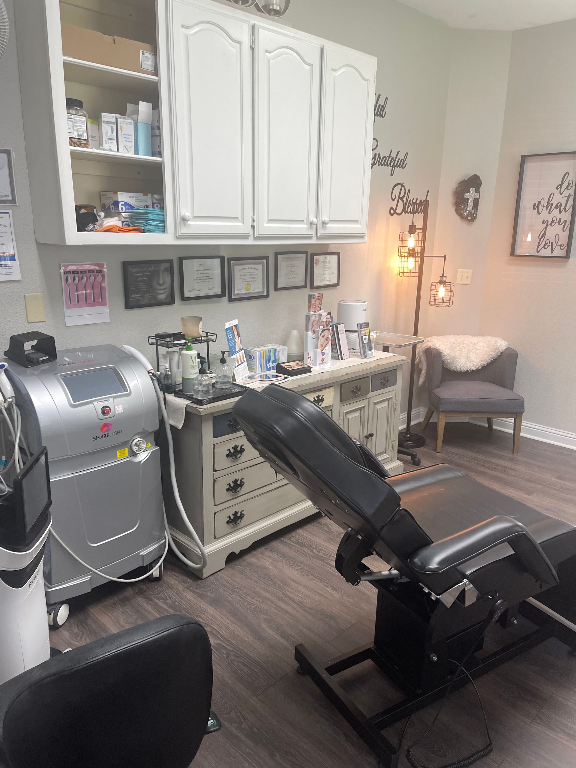 Spa treatment room with laser machine, massage chair, and decorative furniture.