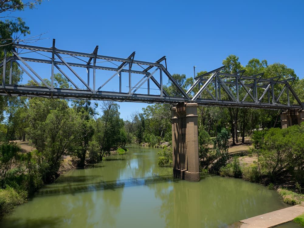 A Bridge Over A River Surrounded By Trees On A Sunny Day — Lohman Contracting in Emerald, QLD