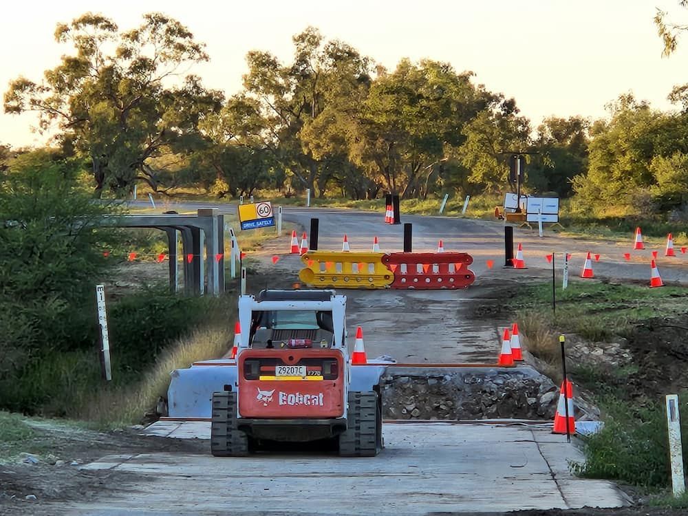 A Bobcat Tractor Is Driving Down A Dirt Road — Lohman Contracting in Katherine, NT
