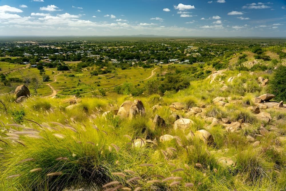 A View Of A Lush Green Field With A Small Town In The Distance — Lohman Contracting in Charters Towers, QLD