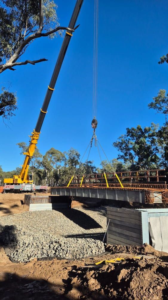 A Crane Is Lifting A Bridge Over A River — Lohman Contracting in Charters Towers, QLD