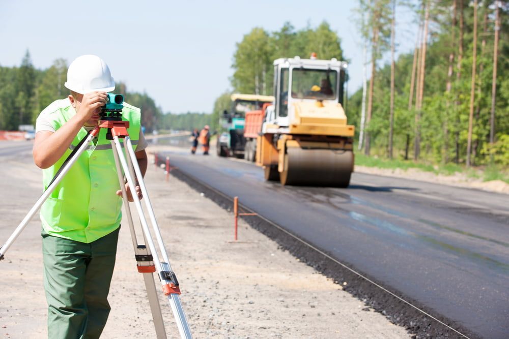 A Man Is Standing On A Tripod Taking A Picture Of A Road Under Construction — Lohman Contracting in Emerald, QLD