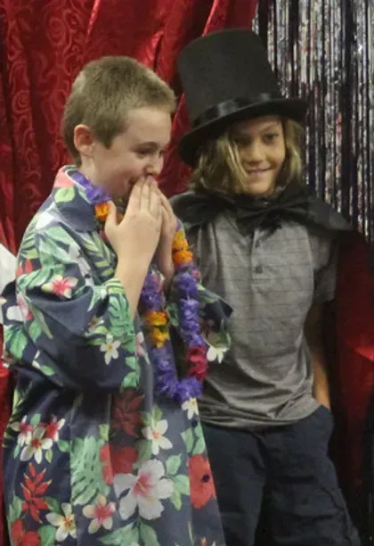 A boy wearing a top hat is standing next to another boy