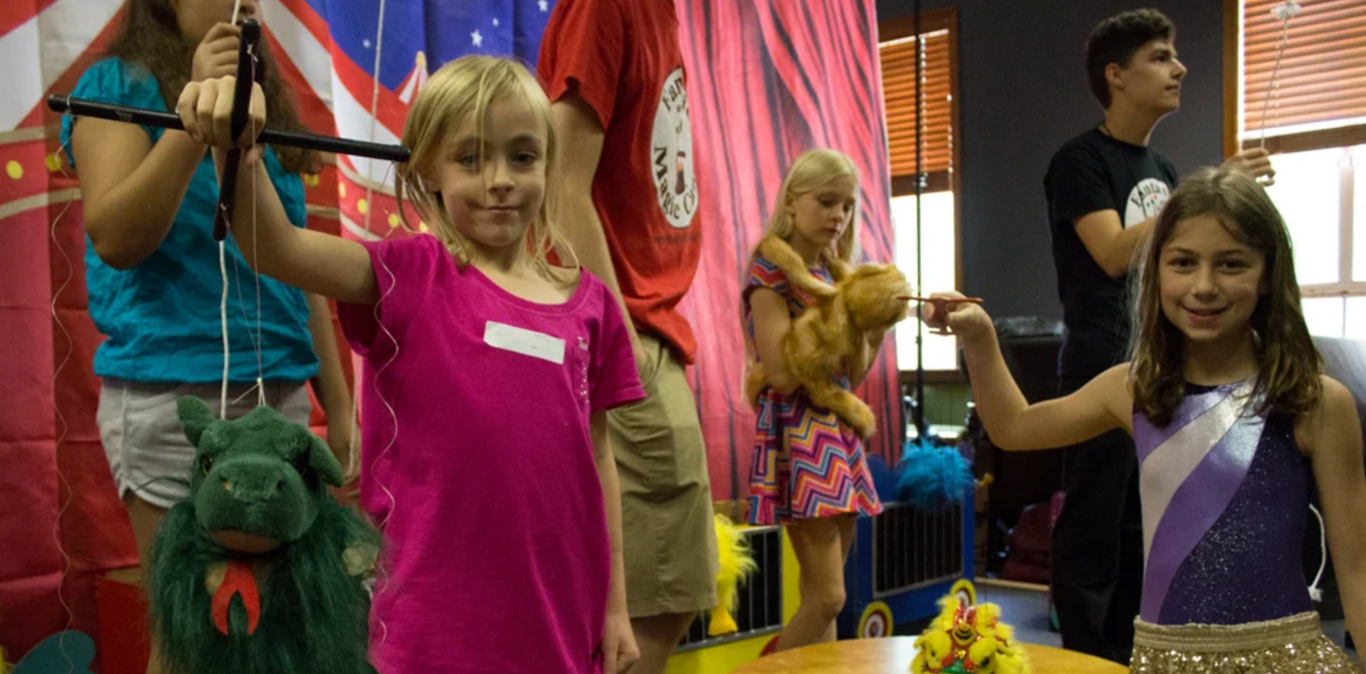 a group of young girls are standing around a table holding stuffed animals .
