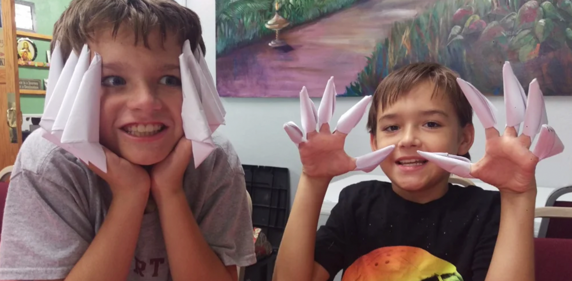 two young boys are making origami animals with their hands .