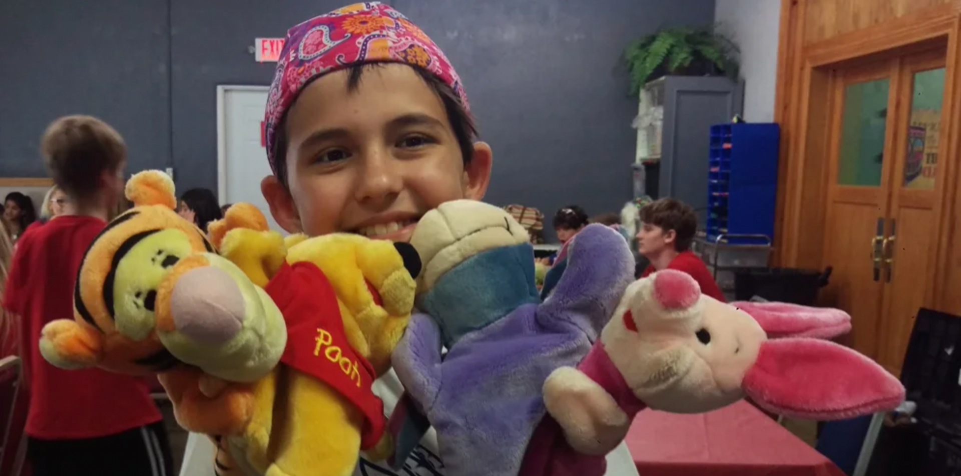 a young boy is holding three stuffed animals in his hands .