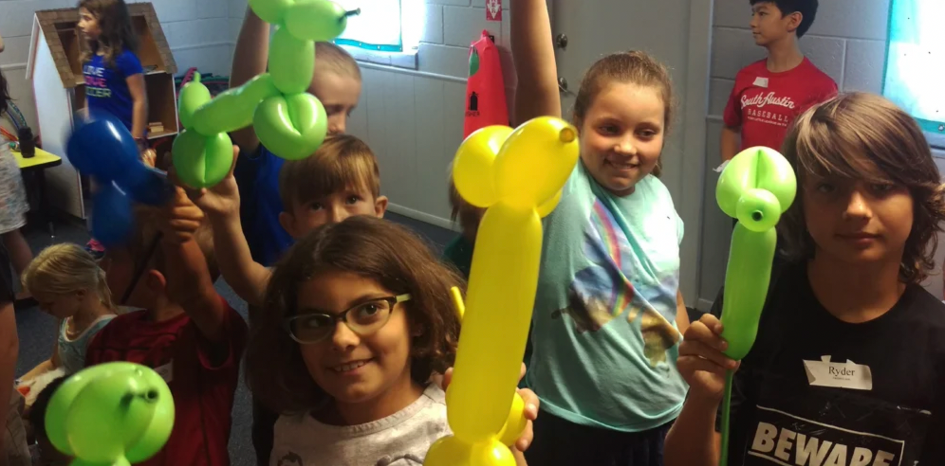 a group of children are holding balloons in their hands .