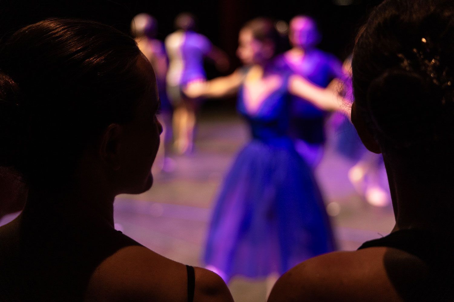 Dos mujeres miran a un grupo de bailarines en un escenario.