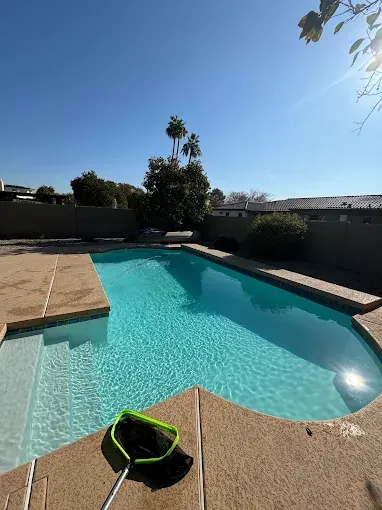 Pool filled with clear turquoise water, sunny day, net on the edge.