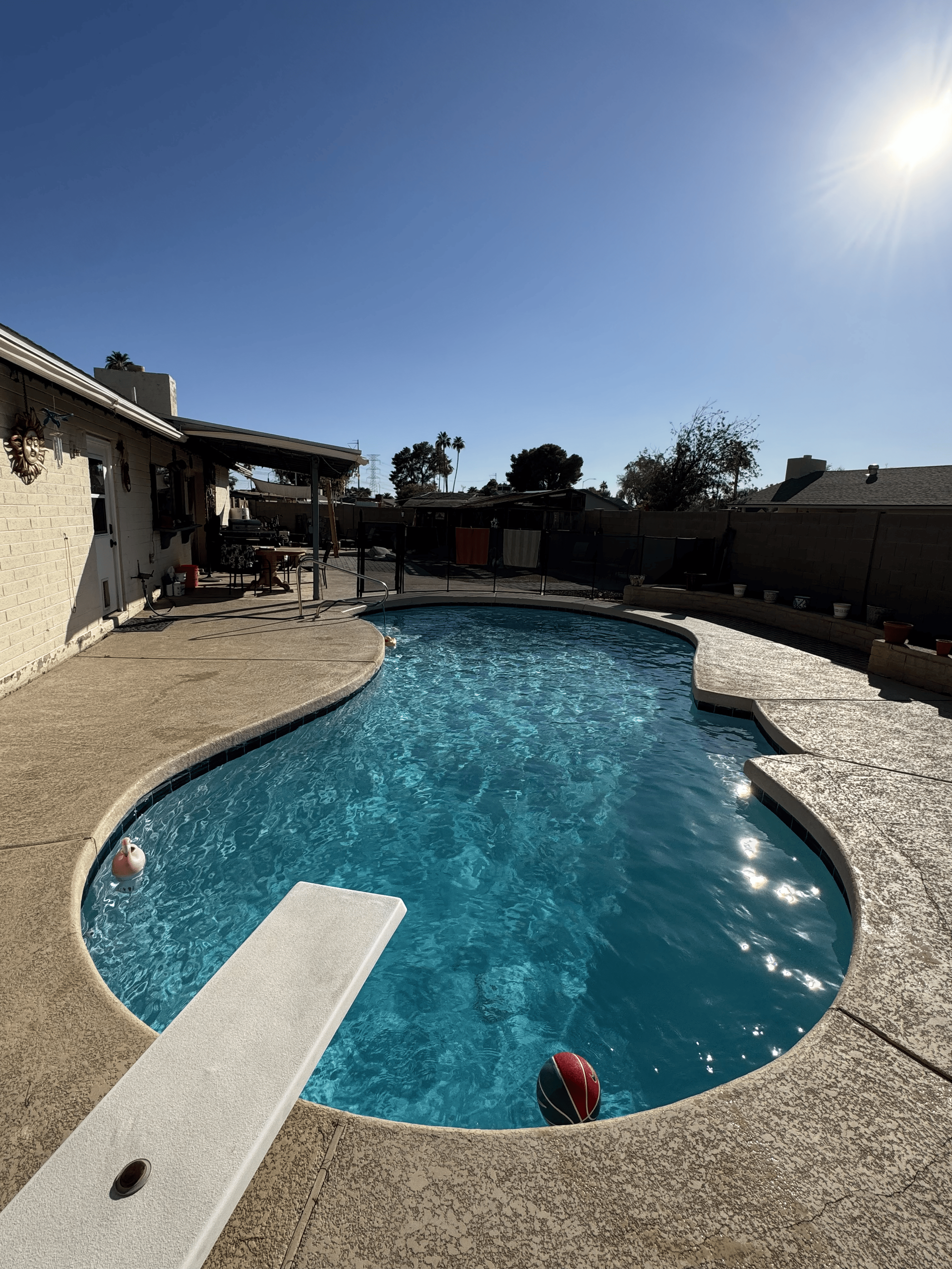Pool with diving board and two red balls on a sunny day.
