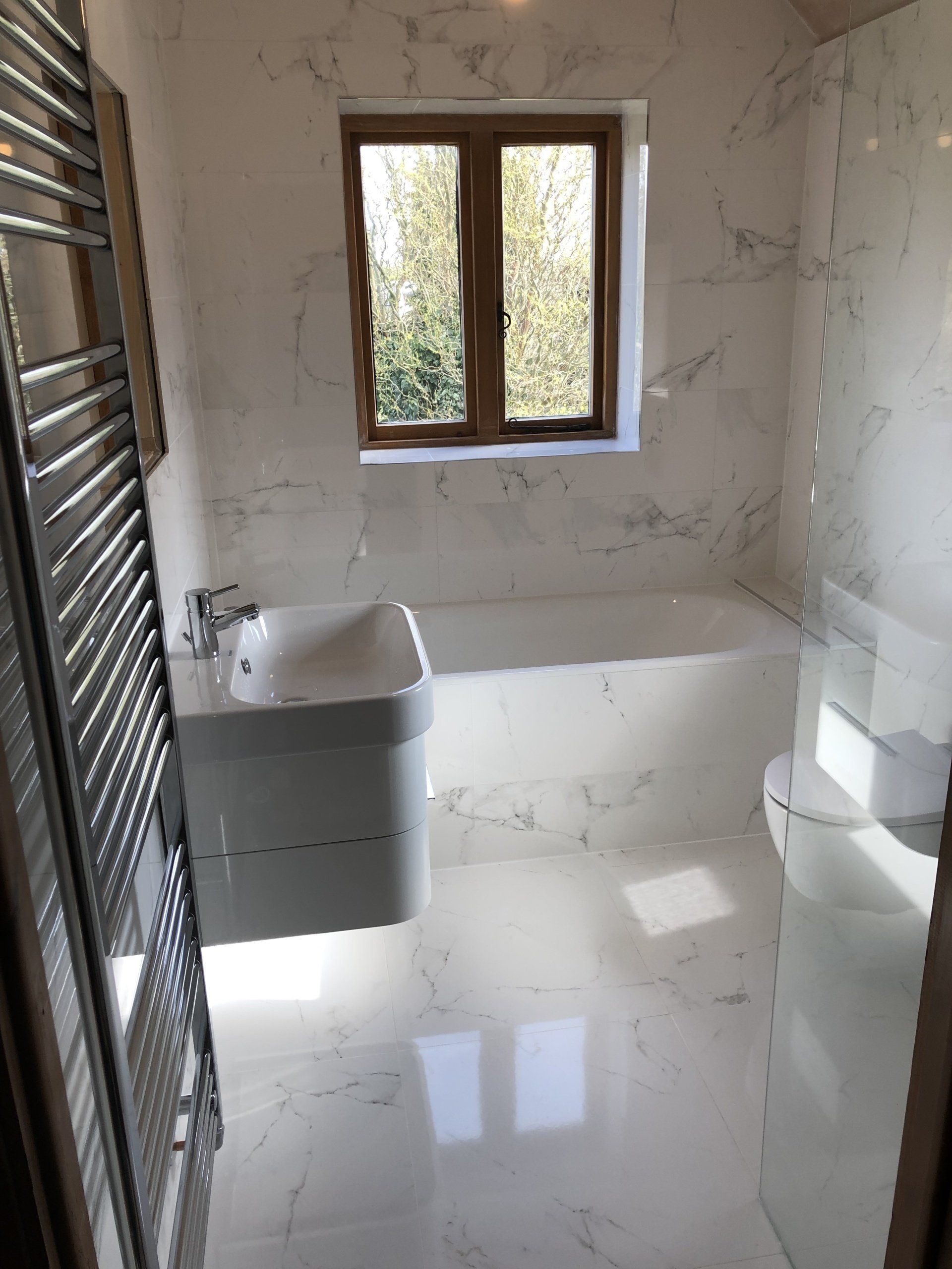 Please look below to find a complete transformation- we created a walk in shower room with beautiful white marble tiles with gloss white furniture.