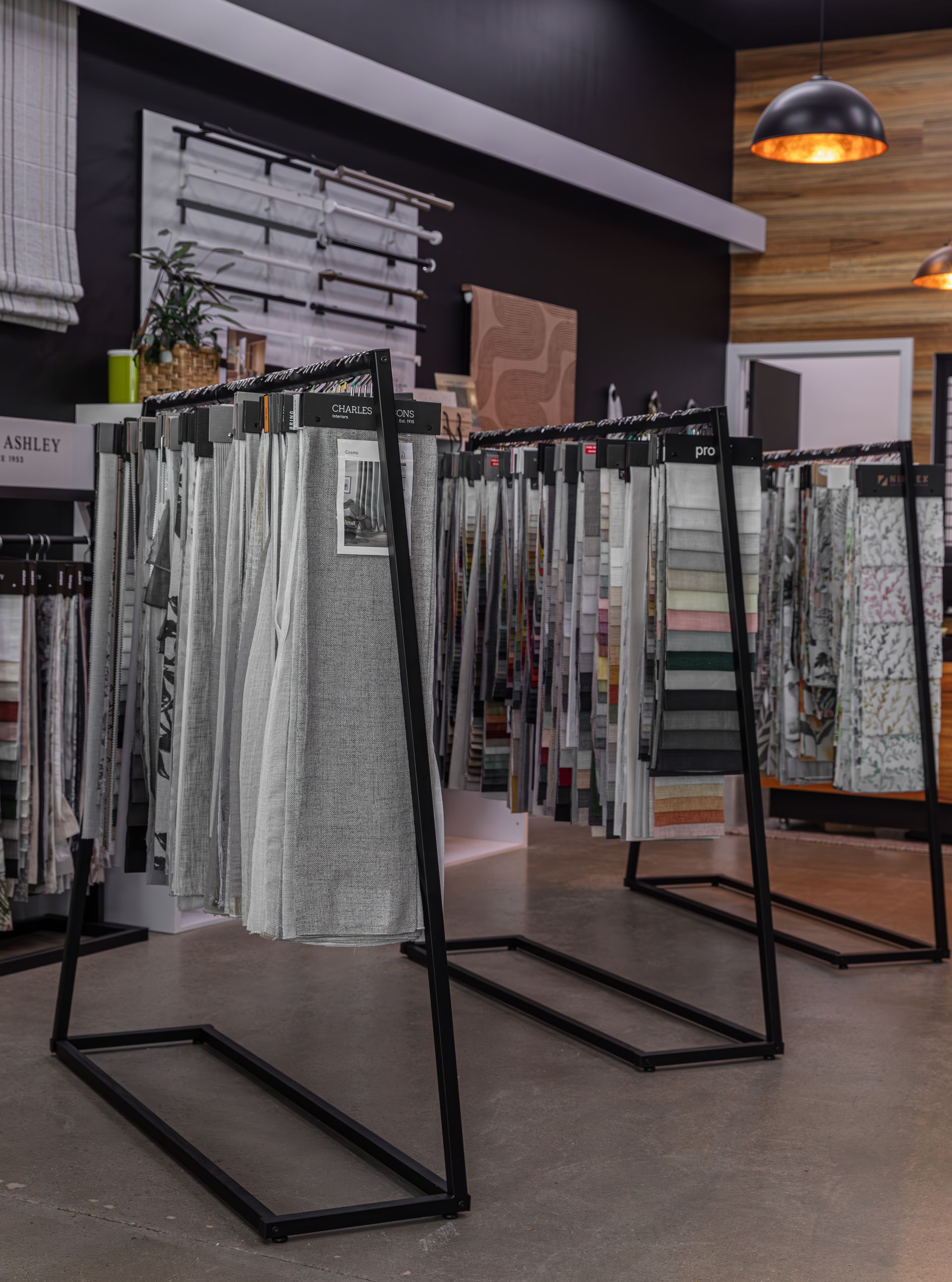 Fabric swatches displayed on black metal racks in a showroom.