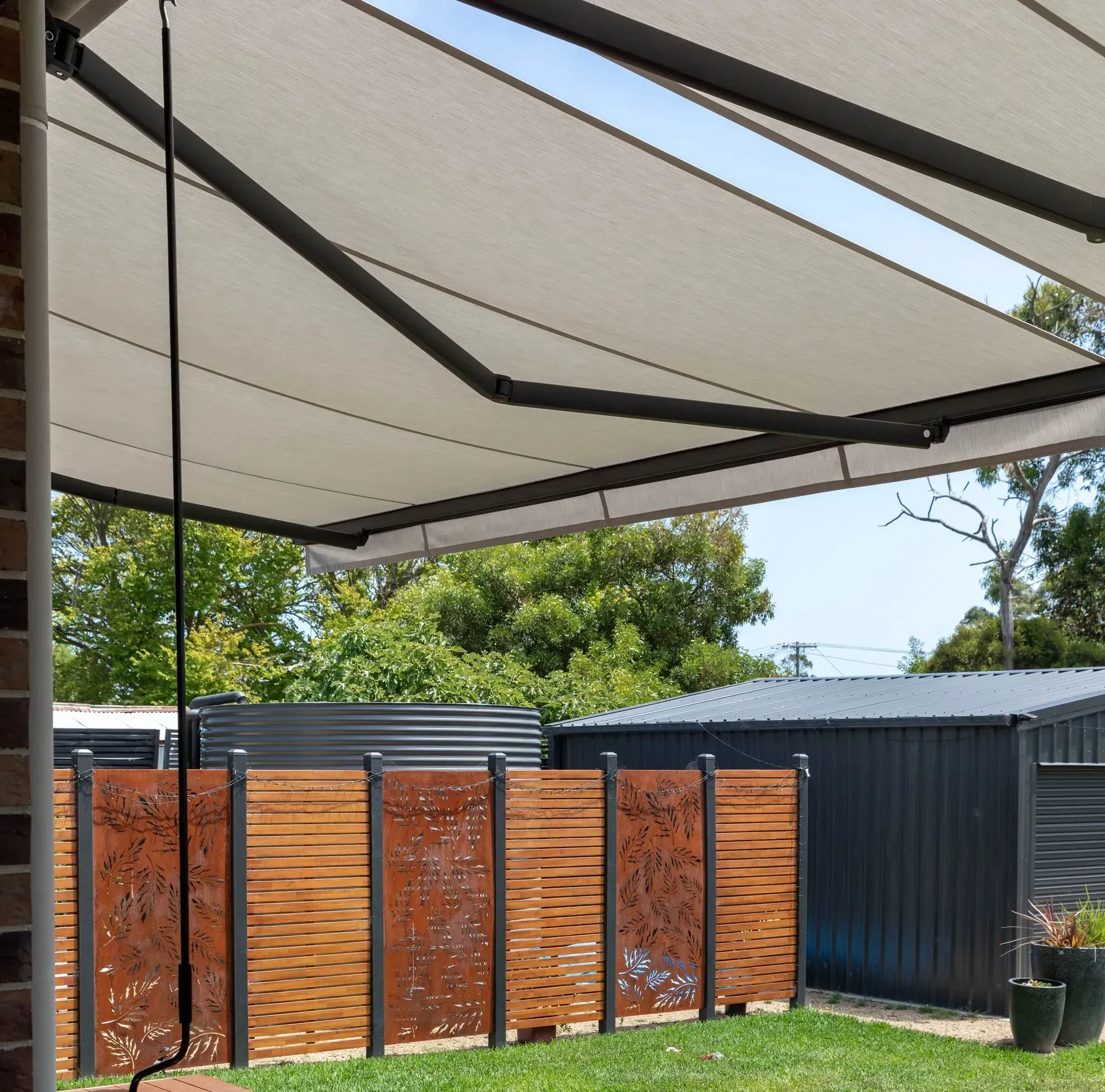 Living room with dark blinds, a large plant, a sofa, and a window overlooking a view.